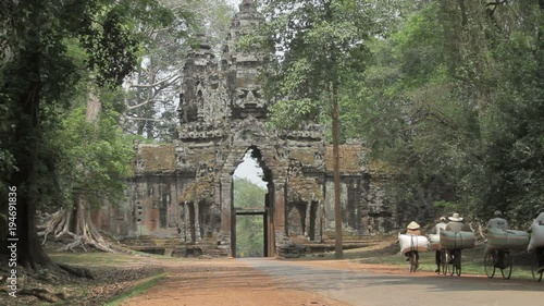Angkor wat north gate with locals riding there bicycles loaded with big bags of rice 