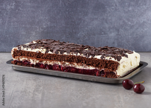 Homemade traditional Black forest sheet cake, topped with cream, dark chokolate and cherry. Selective focus. Copy space. photo