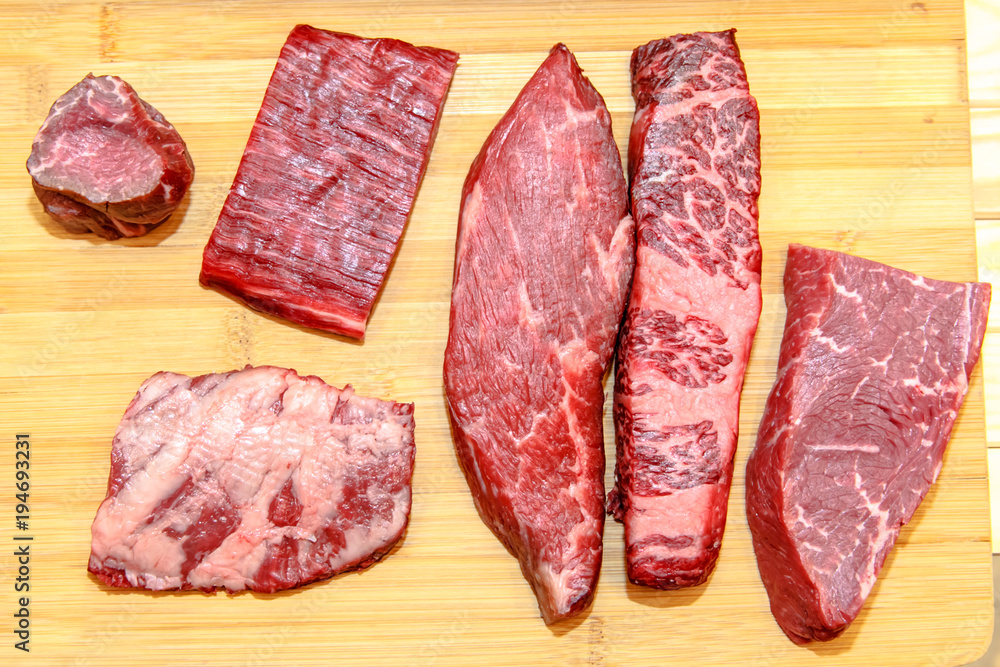 A lot of different steaks of marbled beef lies on the Board, rib eye, tenderloin, Striploin, machete, diaphragm.
