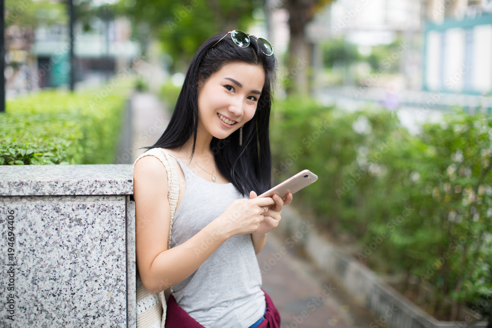 Asia woman walking and using a smart phone in the street in a sunny summer day Asia woman walking and using a smart phone in the street in a sunny summer day
