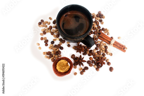 Coffee in a black ceramic cup, coffee beans,  star anise, cinnamon sticks, candy. Isolate on white.