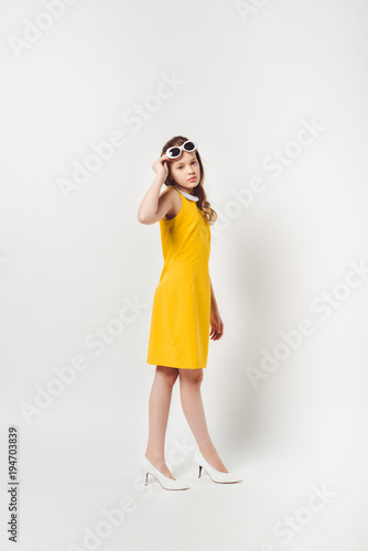 beautiful teenage child in yellow dress on white
