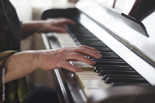 The old lady's hands playing classical music on the piano at home