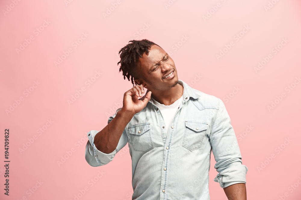 The Ear ache. The sad Faro-American man with headache or pain on a pink studio background. The Ear ache. The sad Faro-American man with headache or pain on a pink studio background.