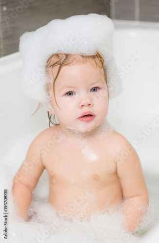 baby girl with soap suds on hair taking bath