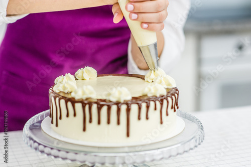 Close up woman`s hand decorating chocolate cake in the kitchen photo