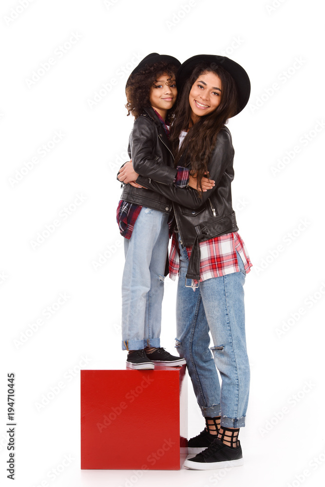 happy embracing mother and daughter in leather jackets and hats mother and daughter isolated on white happy embracing mother and daughter in leather jackets and hats mother and daughter isolated on white