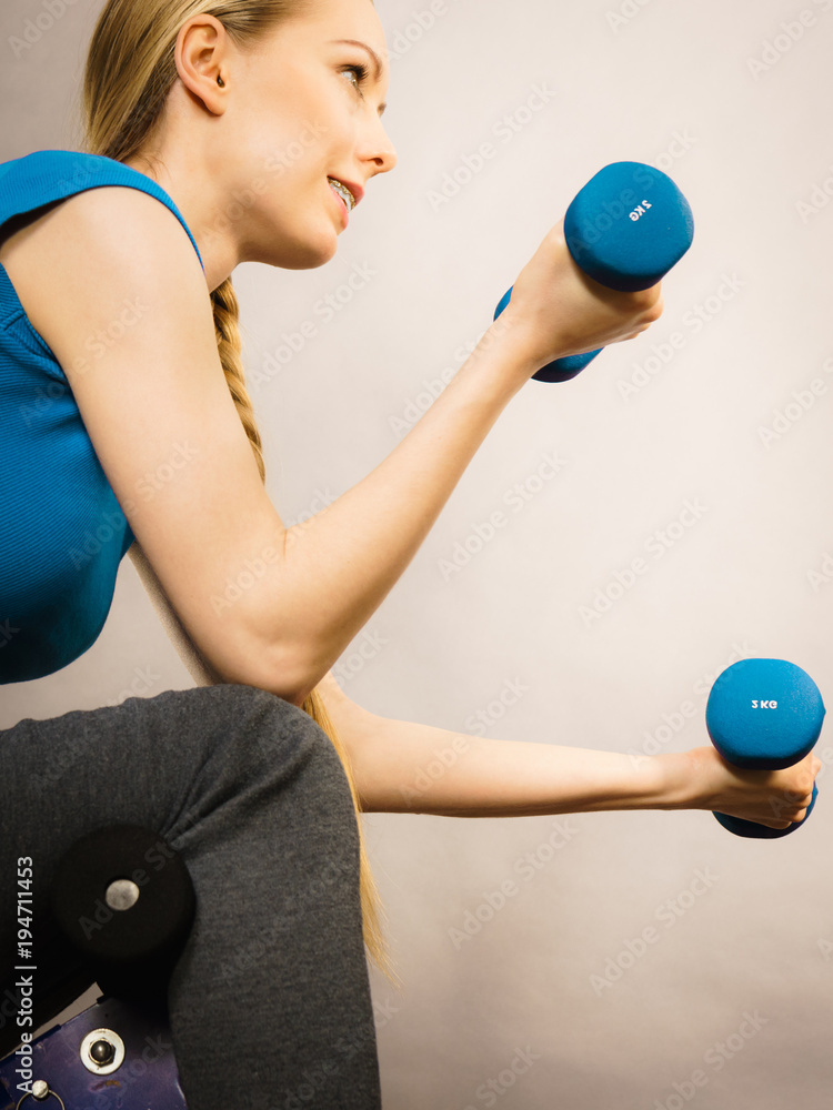 Teenage woman working out at home with dumbbell Teenage woman working out at home with dumbbell
