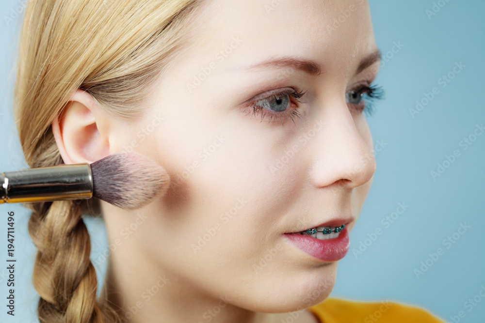 Makeup artist applying with brush rouge on female check Makeup artist applying with brush rouge on female check