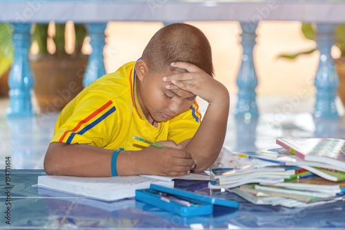 Upset schoolboy doing homework or child with learning difficulties. photo