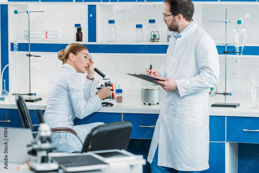 Fototapeta premium scientific researchers in white coats and eyeglasses working together in laboratory