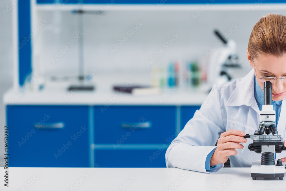cropped shot of female scientist in eyeglasses looking on reagent through microscope in laboratory cropped shot of female scientist in eyeglasses looking on reagent through microscope in laboratory