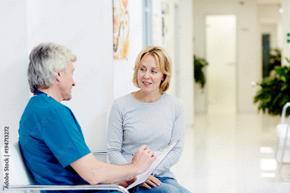Fototapeta premium Surgeon talking with woman in corridor at hospital