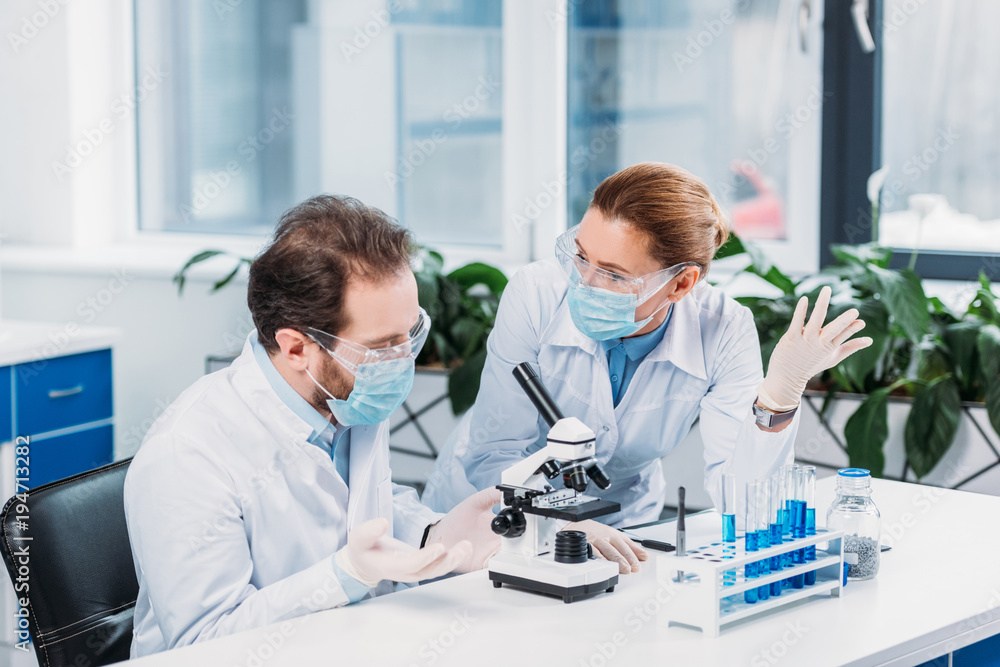 scientists in medical masks and goggles working on scientific research in laboratory scientists in medical masks and goggles working on scientific research in laboratory