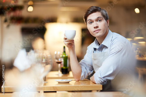 Young businessman drinking coffee at restaurant after hard work