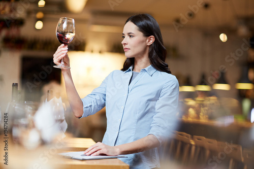 Obraz na plátně Female sommelier at work. She is tasting good red wine