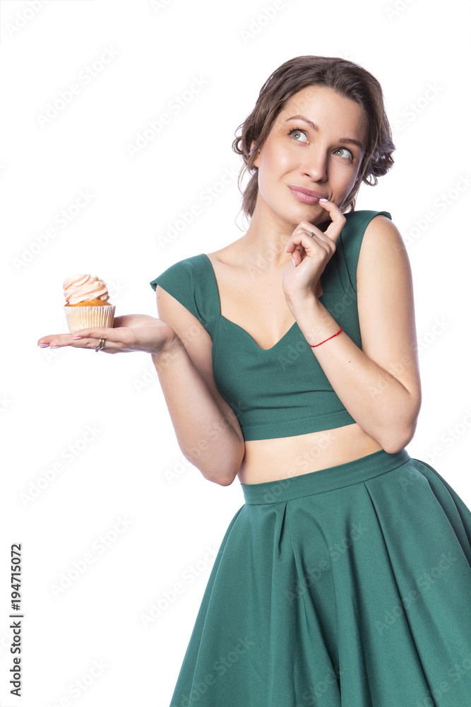 Brunette pretty beautiful caucasian woman in green festive dress showing proposing holding sweet cupcake dessert in her palms. Isolated white background Brunette pretty beautiful caucasian woman in green festive dress showing proposing holding sweet cupcake dessert in her palms. Isolated white background