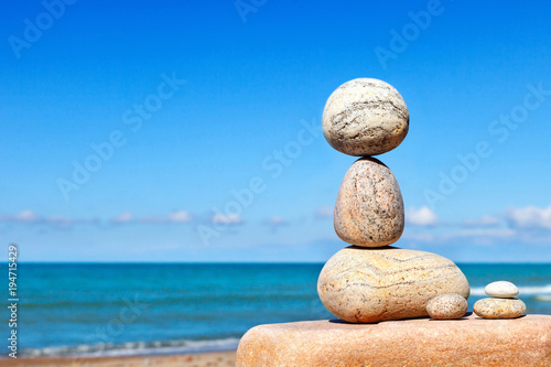 White stones balance on a background of blue sky and sea