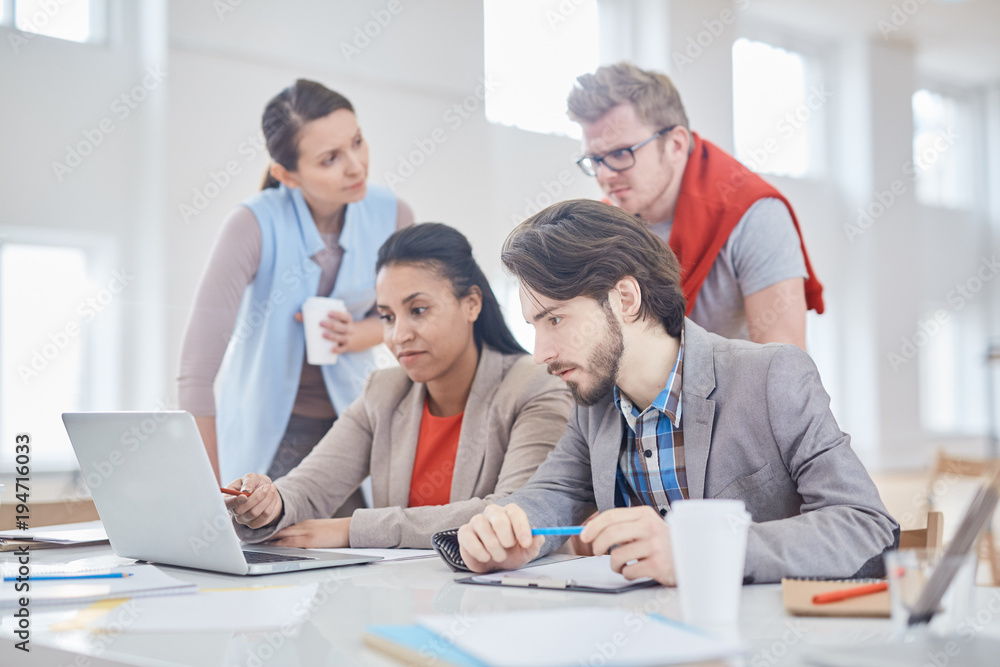 Serious economists or sales managers concentrating on reading online information at meeting