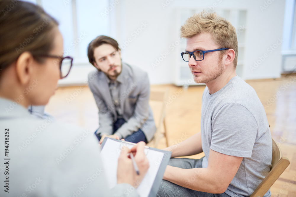 Obraz premium Young businessman looking at psychologist while listening to her recommendations during session