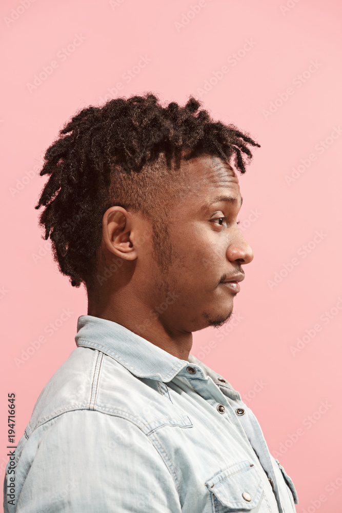 The surprised business Afro-American man standing and looking pink background. Profile view. The surprised business Afro-American man standing and looking pink background. Profile view.