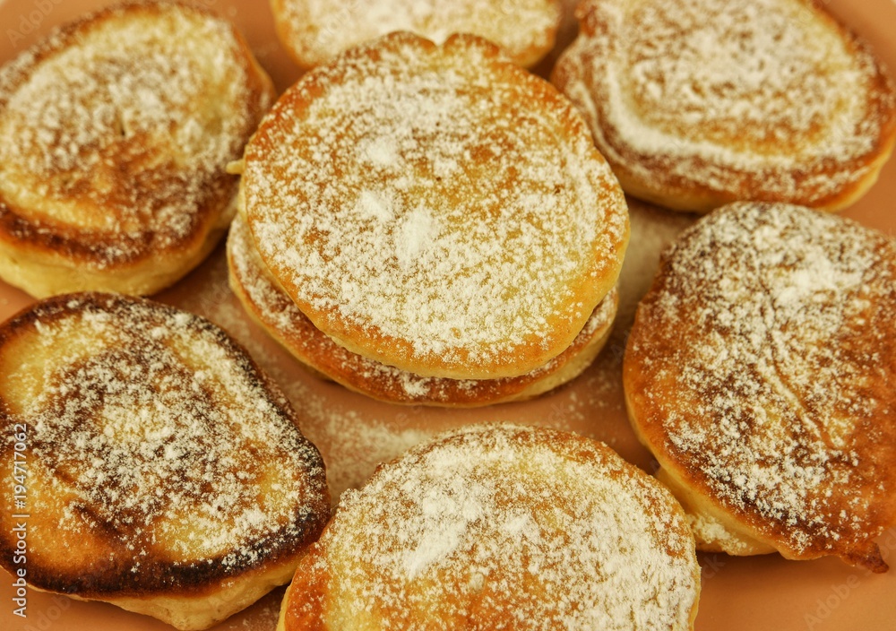 Fritters with powdered sugar on the beige dish Fritters with powdered sugar on the beige dish