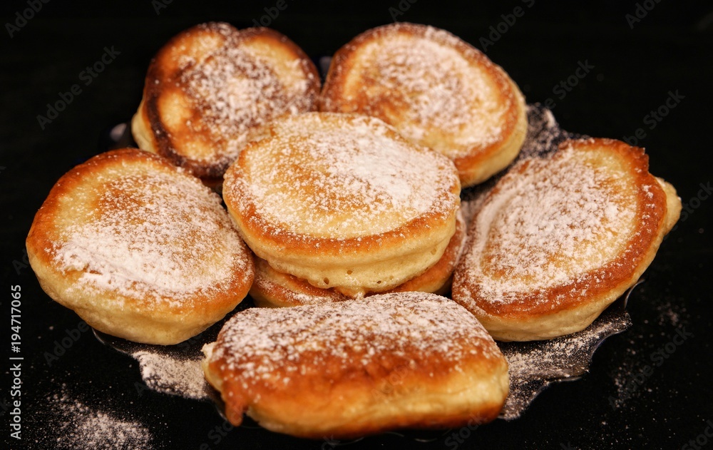 Fritters with powdered sugar on the 
black background
