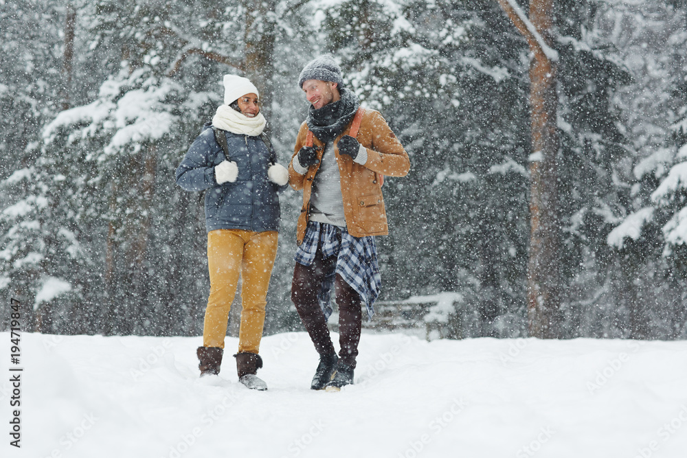 Young couple of trippers in winterwear enjoying their travel on snowy winter day