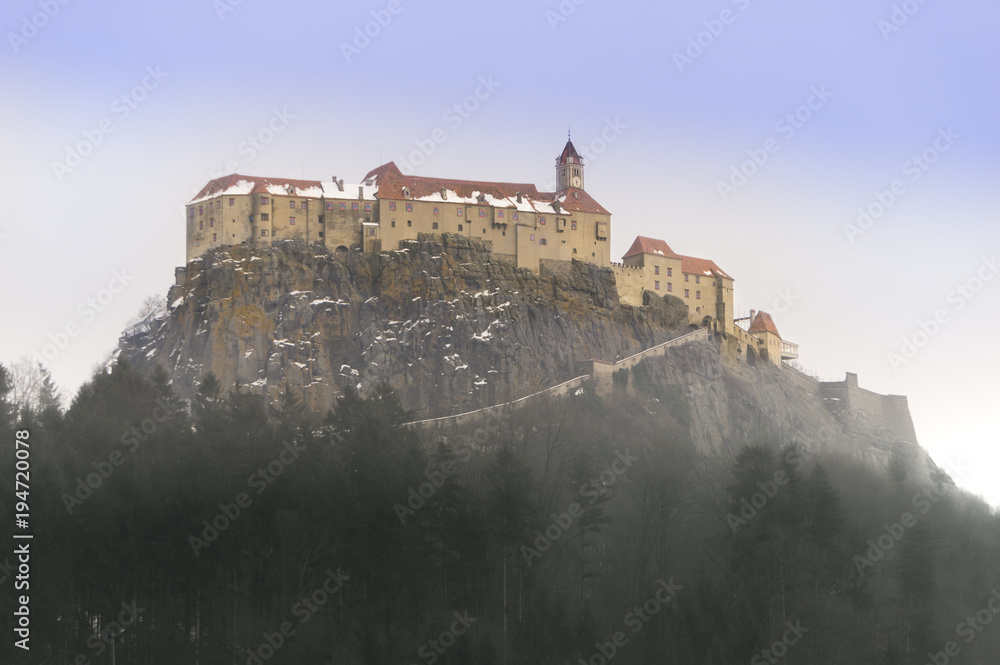 The Riegersburg castle perched on a clifftop above a fog engulfed forest in Styria