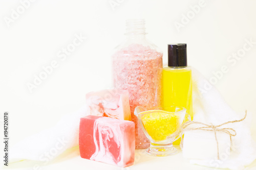 Aromatherapy spa concept. A glass bowl of orange bath salt, a bar of fruit soap, a bottle with yellow oil, white background