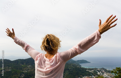 The girl spread her arms in different directions against the background of the sea coast.