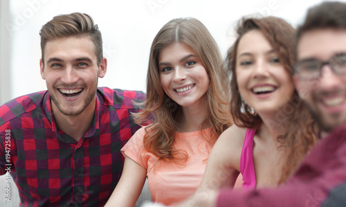 group of cheerful friends sitting on sofa