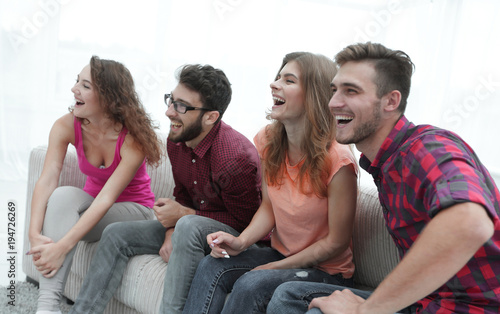 group of smiling young people sitting on the couch
