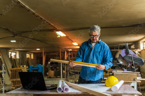 Taking measures. middle aged wood engineer working in his workshop