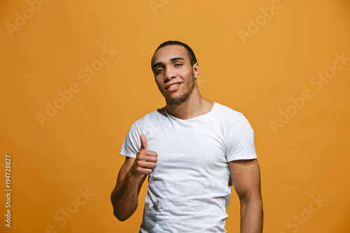 The happy businessman standing and smiling against orange background.