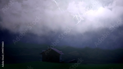 Flashes of light illuminate dark sky, lightning bolts strike above country house