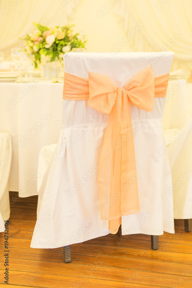 Simple but luxury rich table setting for a wedding celebration in nice cozy restaurant. Wineglasses, plates and bouquet of summer seasonal flowers on a table. Sunlight from a window. Copy space