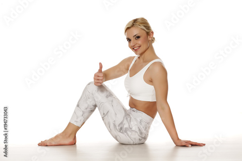 Yoga, sport, training and lifestyle concept - Young blonde woman in white sportswear ishowing thumbs up