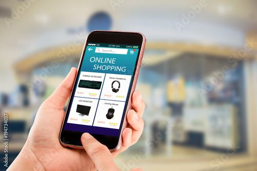 Online shopping concept.Hands holding mobile phone on blurred shop as backround