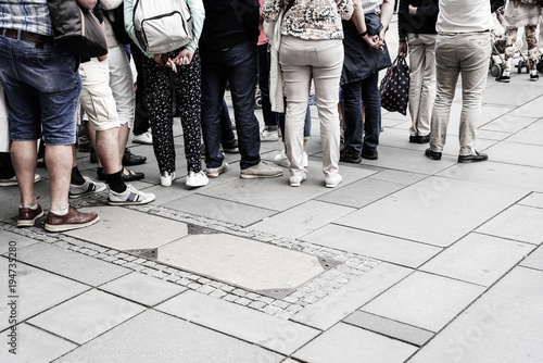 People waiting in line to enter building from waist down photo