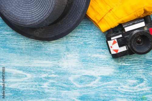 Vacation concept. Old vintage camera and a hat on blue wooden background photo