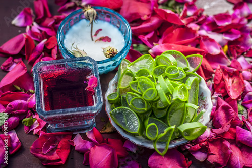 Close up of a herbal face pack consisting of Aloe Vera gel,honey,milk cream,lemon and rose with rose water and rose petals on wooden surface in dark Gothic colors.This face pack removes the dull skin. photo