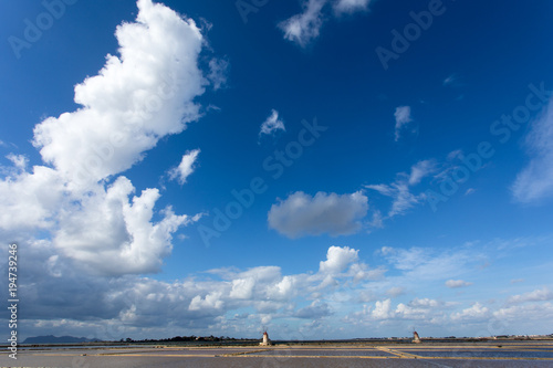 Marsala,Trapani - Sicilian salt lakes with wind mills and salt piles, during a sunny day with blue sky and clouds.