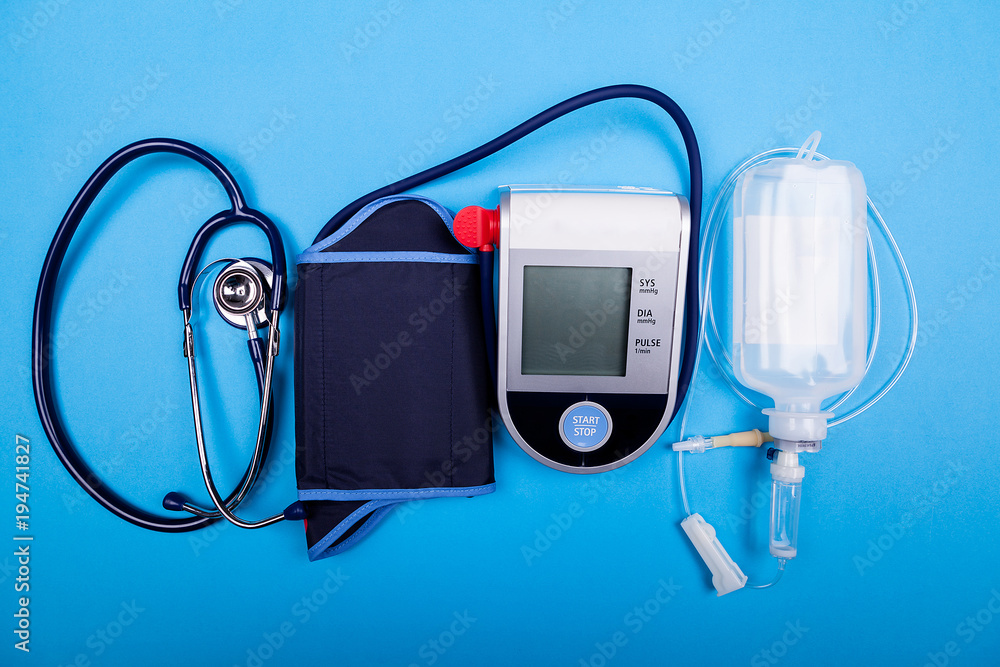 Blood presure mesurement tool next to a stethoscope and other medical devices on blue background