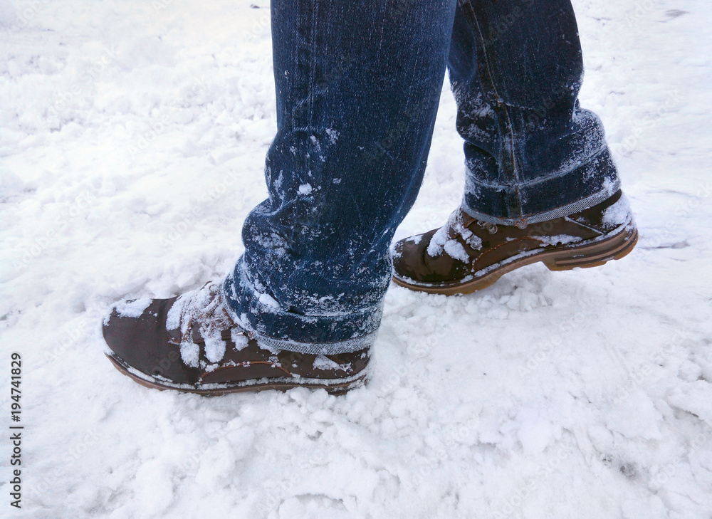 Boots and jeans in the snow. Female legs in jeans and winter boots ...