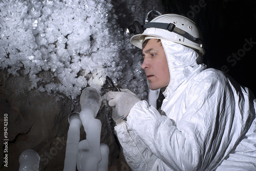 cave explorer carefully examines the structure of the ice formations through a magnifying glass photo