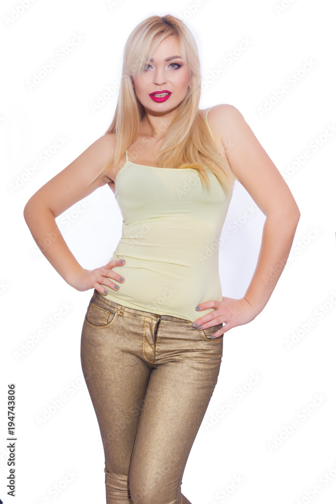 Studio portrait of a beautiful young blond woman with long hair, dressed in a summer yellow jersey and golden jeans. Concept: summer mood. Isolate. Copy space Studio portrait of a beautiful young blond woman with long hair, dressed in a summer yellow jersey and golden jeans. Concept: summer mood. Isolate. Copy space