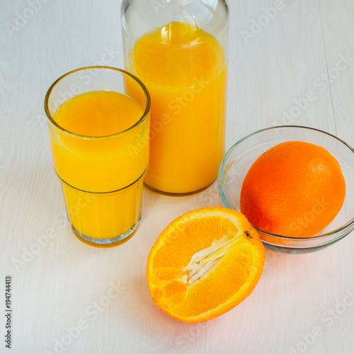 Orange juice in a glass bottle and glass on a white background