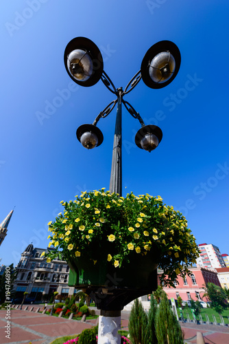 Lamp post with flower basket over blue sky