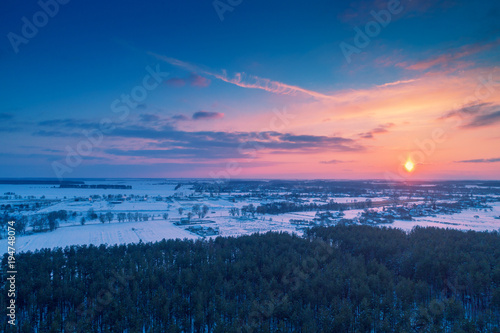Aerial evening view at countryside and snowy fields during sunset